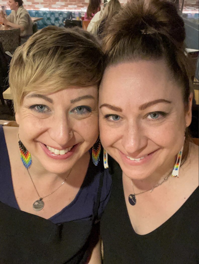 Two women pose with their faces close together. 